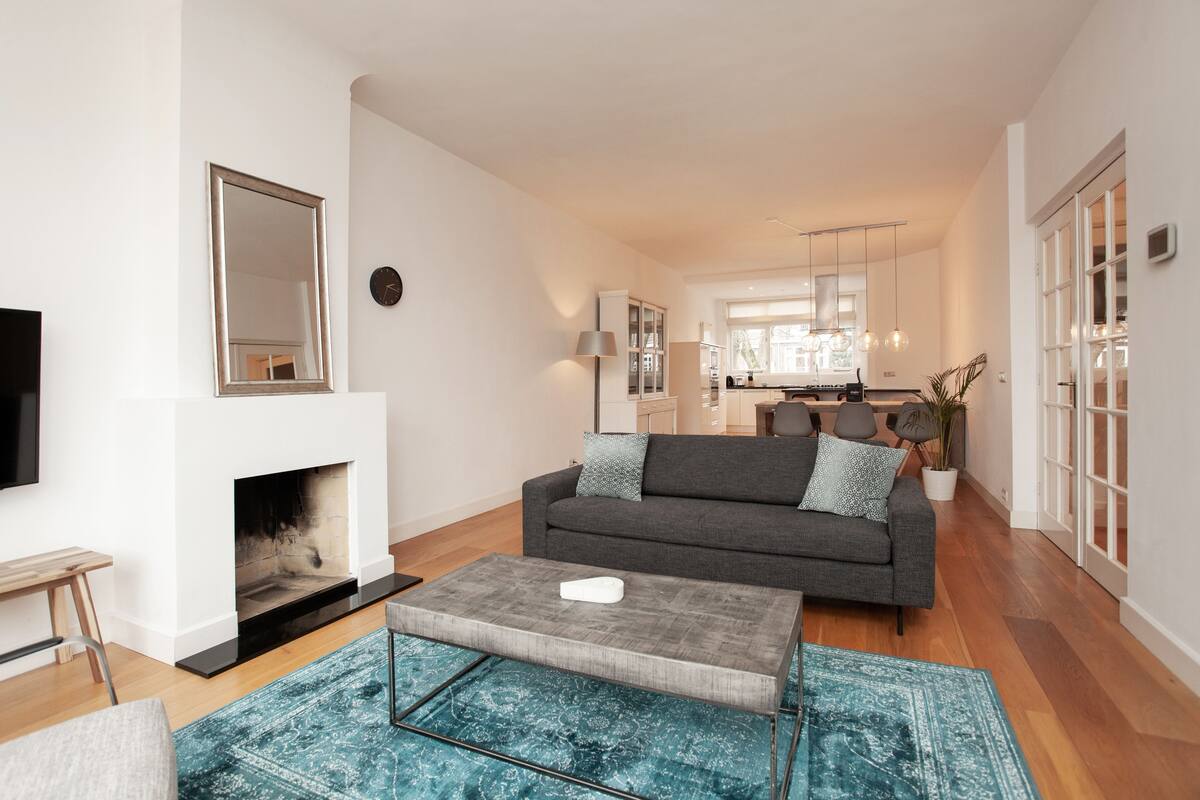 Ein modernes Wohnzimmer mit Kamin, einer Couch, einem Couchtisch und einer Küche im Hintergrund.