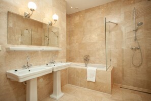 Een moderne badkamer met twee wastafels, een bad en een douchecabine.