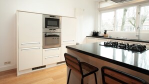 Een moderne keuken met witte kasten, een inbouwoven, een magnetron en een gasfornuis.
