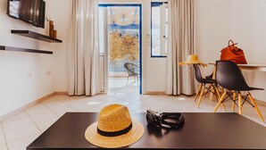 Un soggiorno moderno con televisione, un tavolo da pranzo con sedie, un cappello e una macchina fotografica sul tavolo.