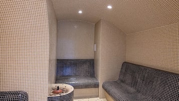 Un cuarto de spa con paredes y suelo de baldosas, una zona de estar circular y dos sofás.