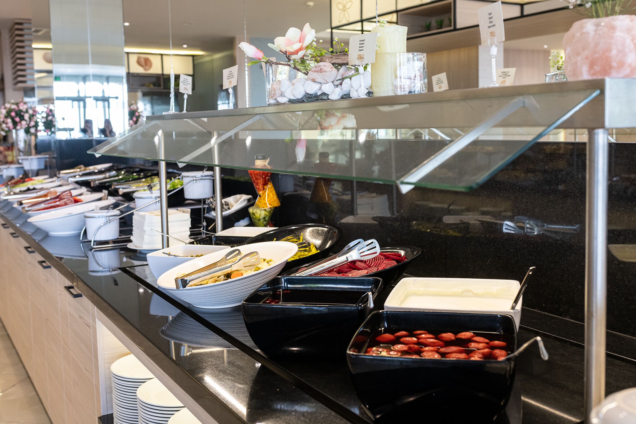 A buffet counter with various food items and utensils.