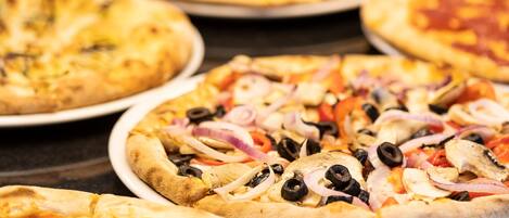 A variety of pizzas with different toppings on white plates.