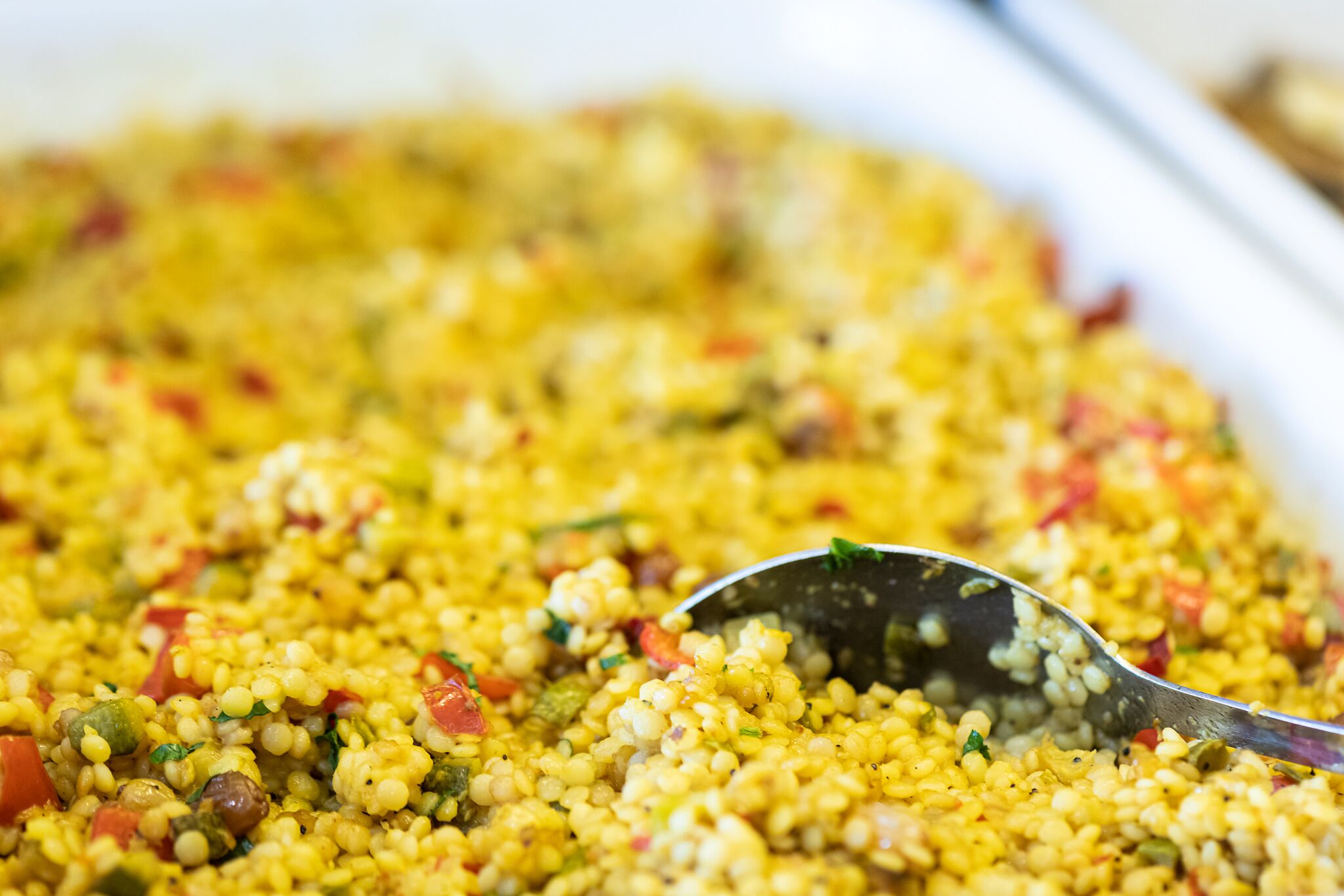 A close-up of a dish with couscous, vegetables, and herbs.
