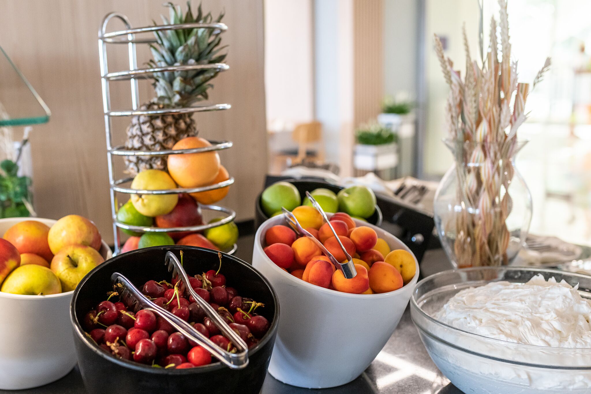 Une table de buffet avec divers fruits et un bol de crème fouettée.