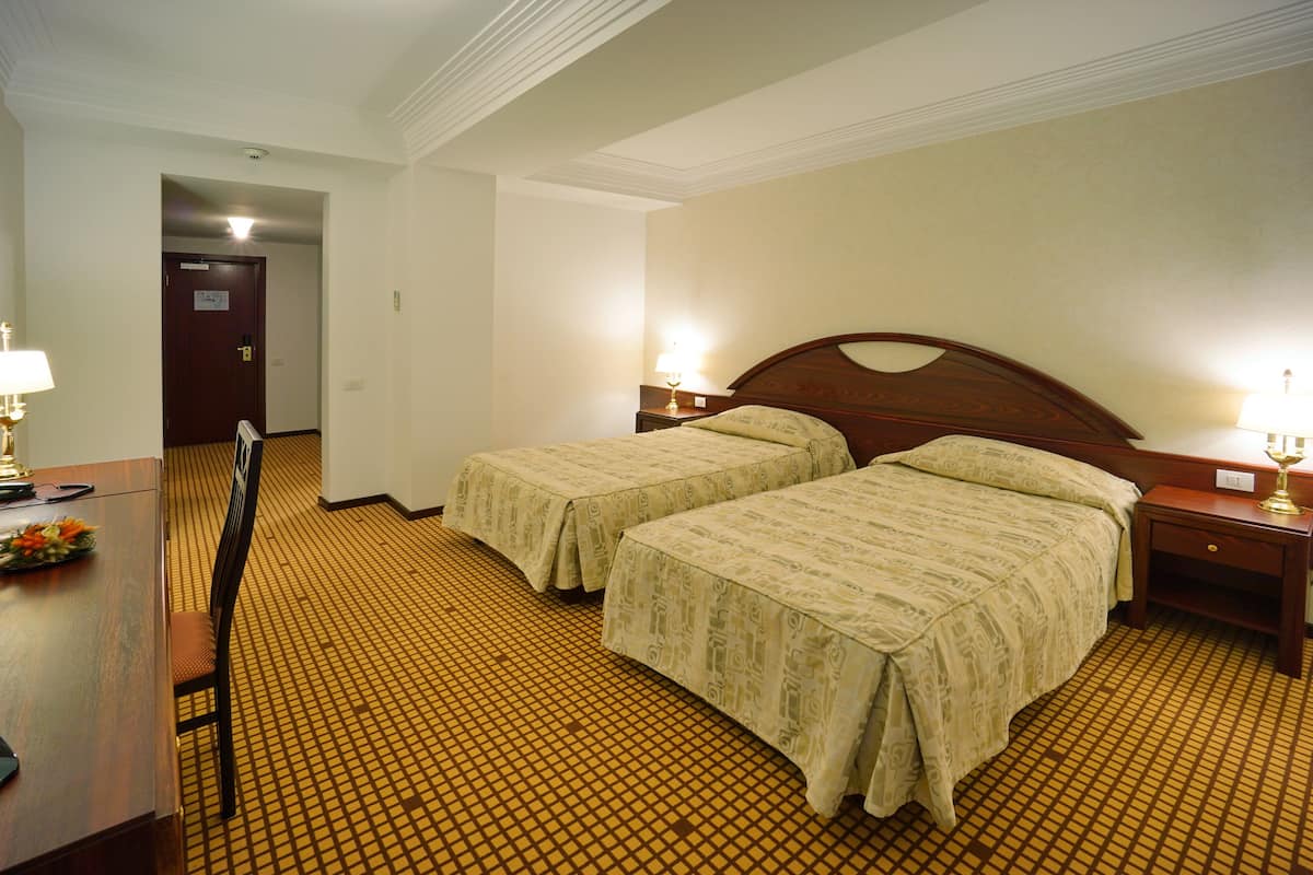 A hotel room with two beds, a desk, and a chair.