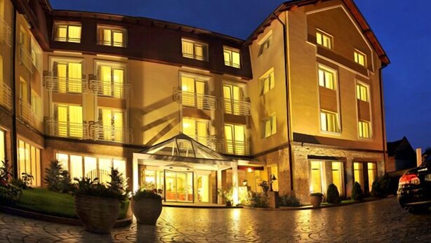 Un hotel de varios pisos con un patio central, ventanas amplias y una entrada bien iluminada.