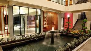 A courtyard with a water feature, a staircase, and a red wall. - Euanjitt Chill House (Khon Kaen)