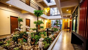 A hotel lobby with a central garden, multiple doors, and a staircase. - Euanjitt Chill House (Khon Kaen)