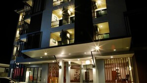 A multi-story hotel with balconies, a car parked in front, and a well-lit entrance. - Euanjitt Chill House (Khon Kaen)