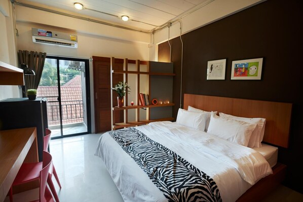 Una habitación de hotel moderna con una cama grande, un escritorio y un ventanal corredero al exterior.