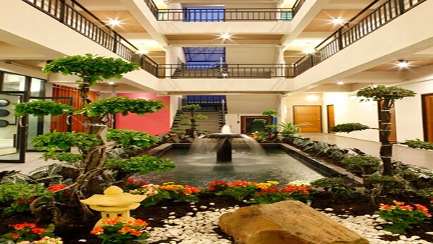A multi-level atrium with a central water feature, surrounded by various plants and a decorative lantern. - Euanjitt Chill House (Khon Kaen)