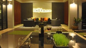 A modern living room with a sofa set, a table with a bottle of wine and glasses, and a sign reading "Chill House". - Euanjitt Chill House (Khon Kaen)