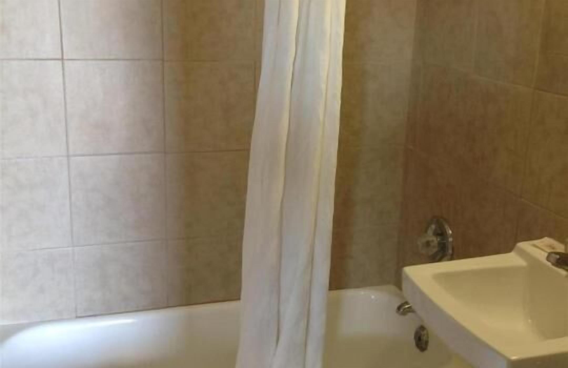 Een badkamer met een bad, een wastafel en betegelde wanden.
