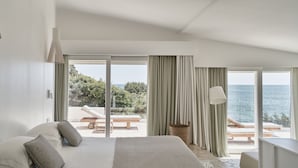 A bedroom with a large bed, a view of the sea, and a balcony with outdoor seating. - Falkensteiner Resort Capo Boi (Villasimius)