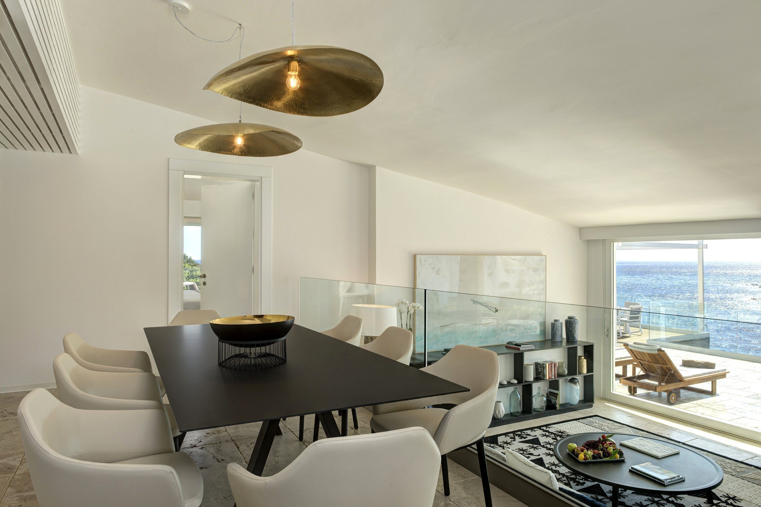 A modern dining area with a black table, white chairs, and a large pendant light.