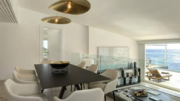 A modern dining area with a black table, white chairs, and a large pendant light.