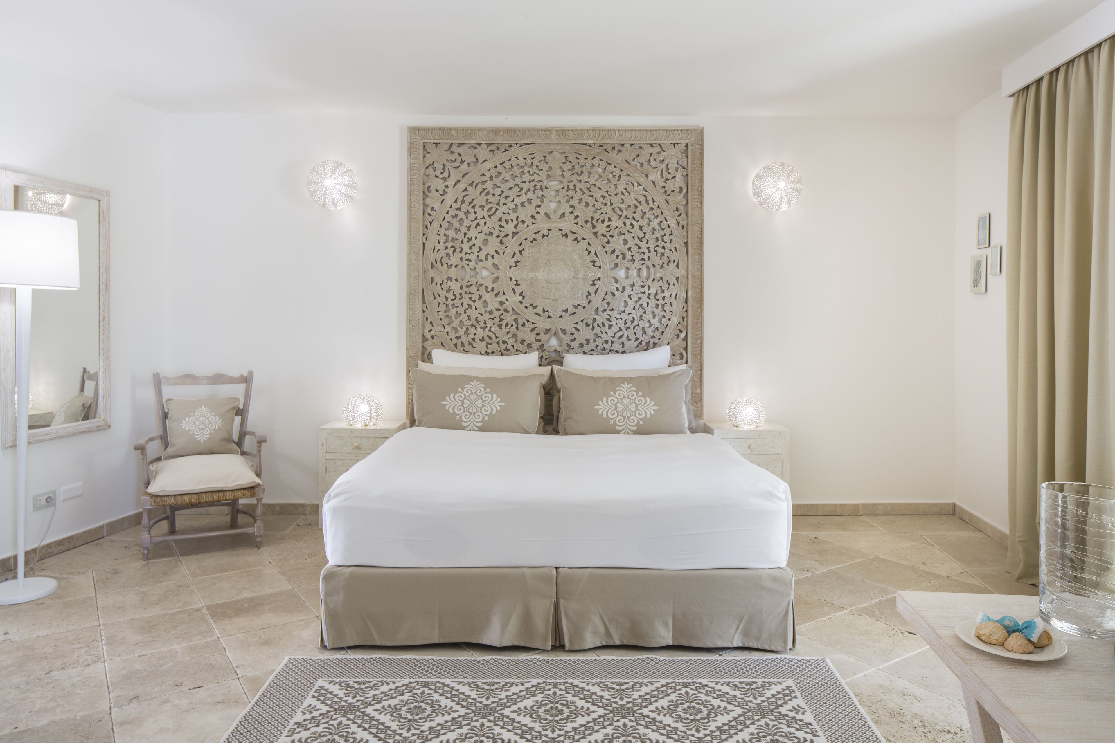 Un dormitorio con una cama grande, una silla, una mesita de noche y un panel decorativo en la pared.