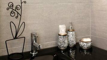Un baño moderno con un lavabo negro, un espejo y adornos en la encimera.