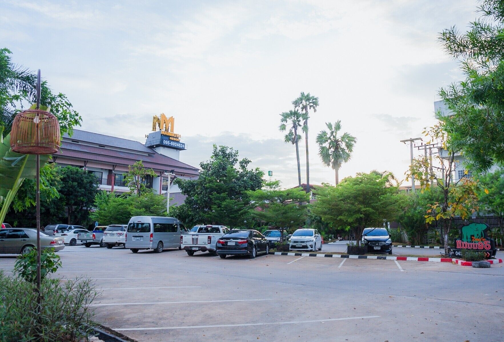 A parking lot with several cars and a building with a sign that reads "Wai Mot Resort."