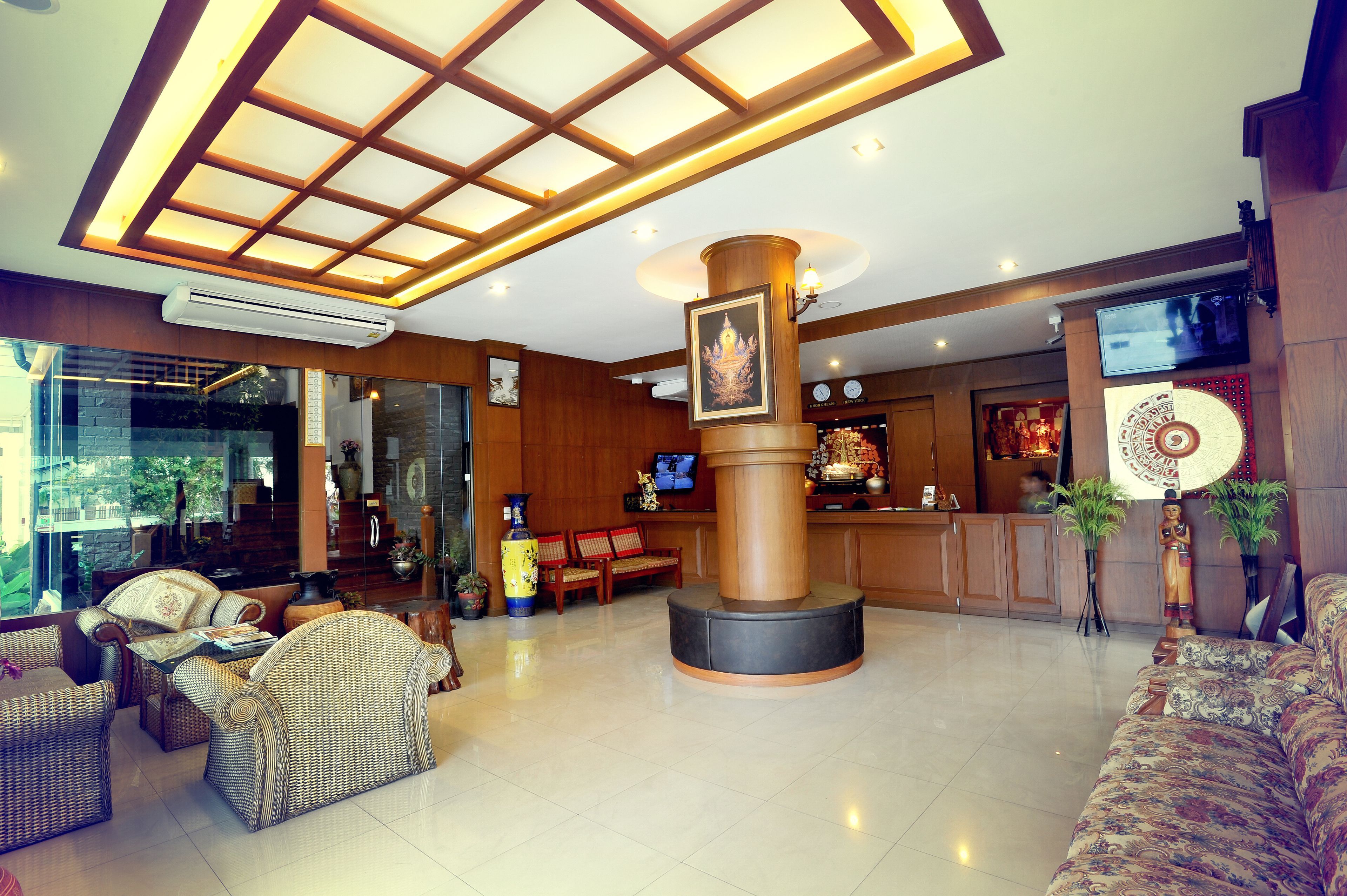 A lobby with a reception desk, seating area, and a large pillar with a framed picture.