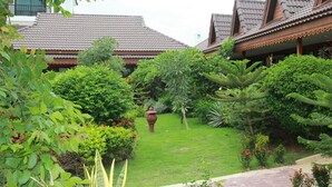 A traditional building with a tiled roof and a well-maintained garden with various plants and a decorative pot. - Mammoth Resort (Khon Kaen)