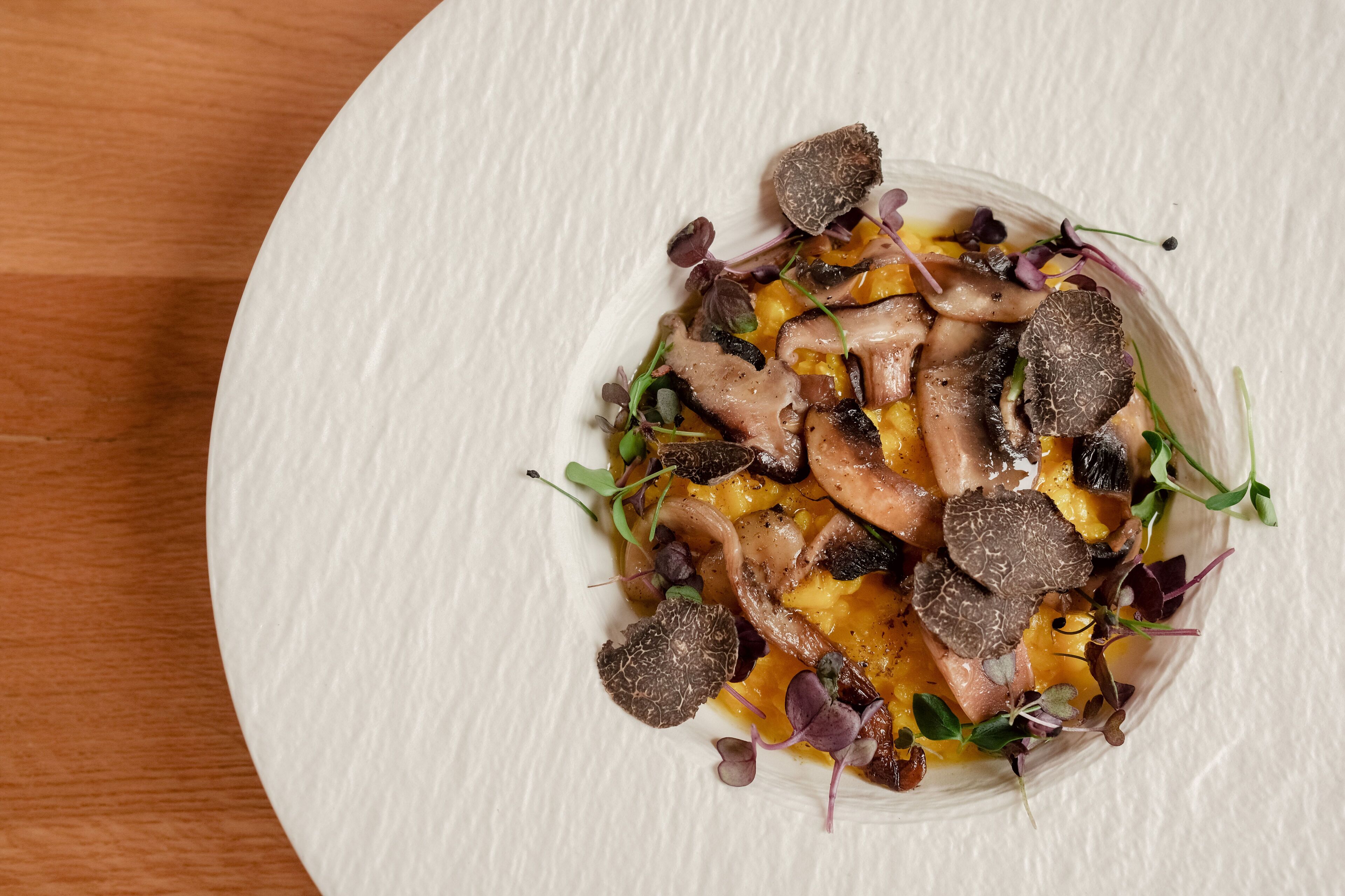 Une assiette blanche contenant un plat de champignons et de légumes verts.