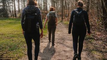 Tre persone camminano su un sentiero sterrato in una zona boschiva.