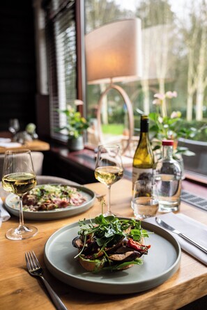 A dining table with plates of food, wine glasses, and bottles. - Witte Berken Natuurhotel (Epe)