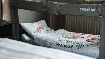 Een bed met hoofdbord met de tekst 'KOELSTRA', een sierlijk gebloemd kussen en een wit laken.