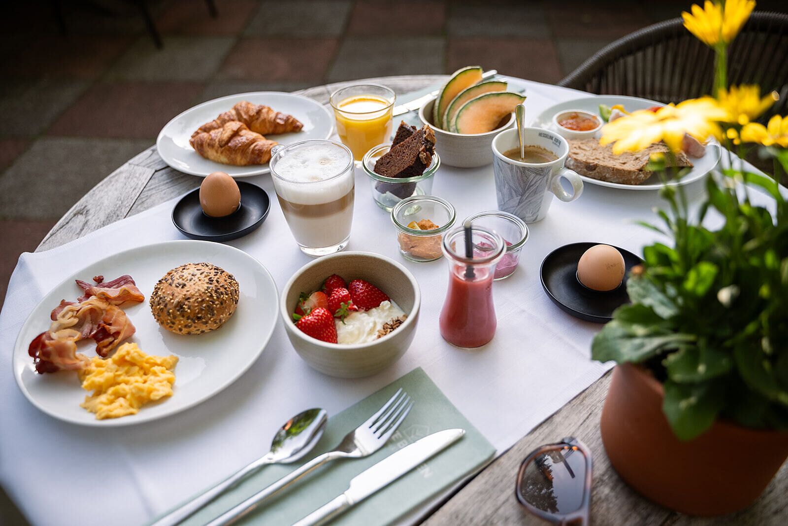 Una mesa de desayuno con platos de huevos, tocino, tostadas y un batido.