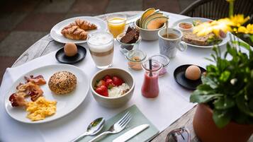 Una mesa de desayuno con platos de huevos, tocino, tostadas y un batido.