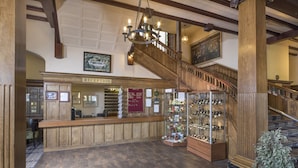 Un espace d’accueil comprenant un comptoir en bois, un escalier et une vitrine en verre où sont exposés divers objets.