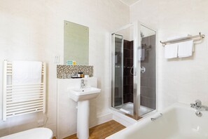 Un baño con inodoro, lavamanos, ducha y bañera.