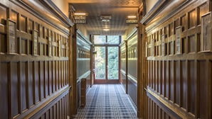 Un couloir aux murs lambrissés et au sol à carreaux mène à une porte en verre. Des panneaux indiquent « Salon MacRae » et « Hommes ».