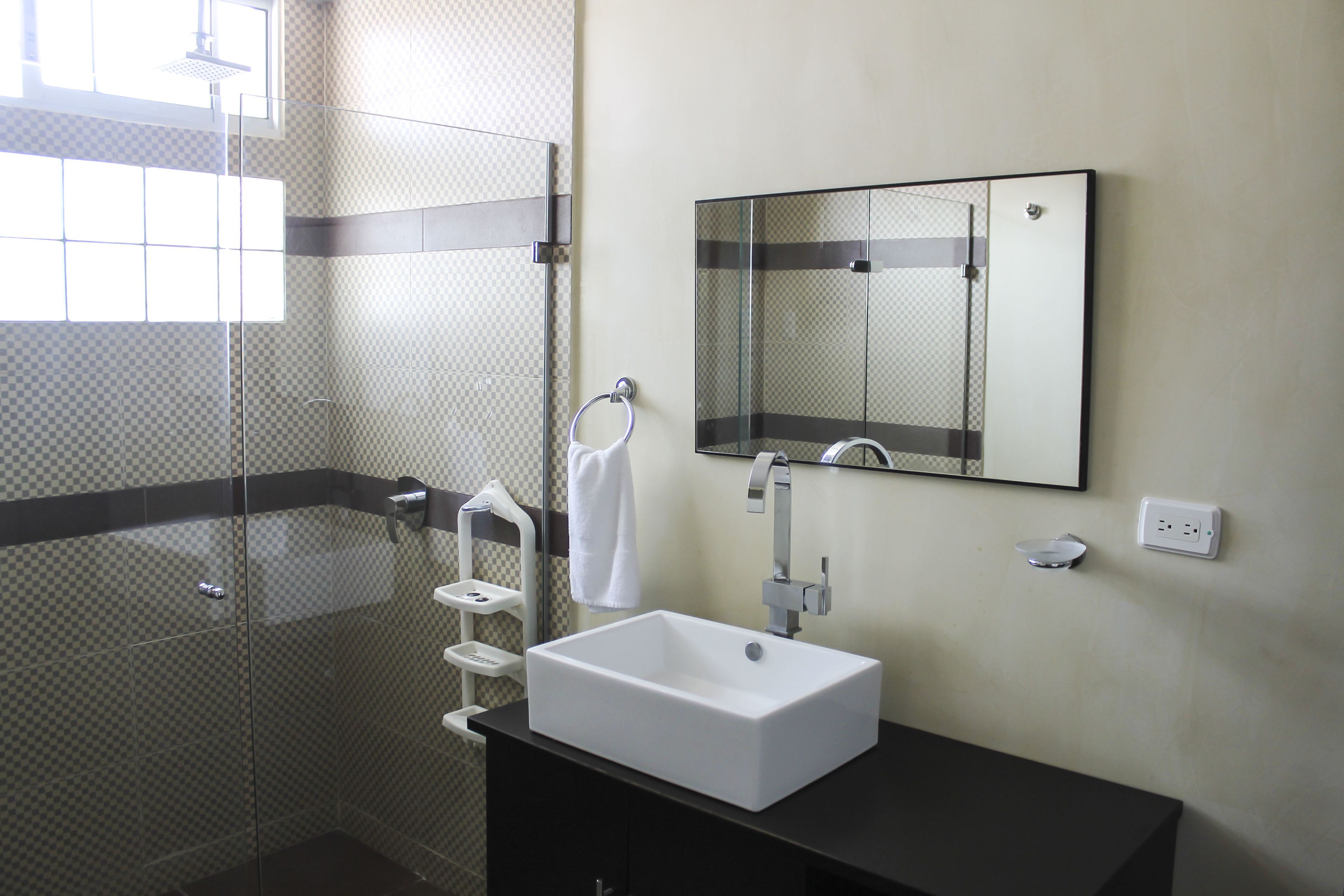 A modern bathroom with a glass-enclosed shower, a white sink, and a mirror above it.