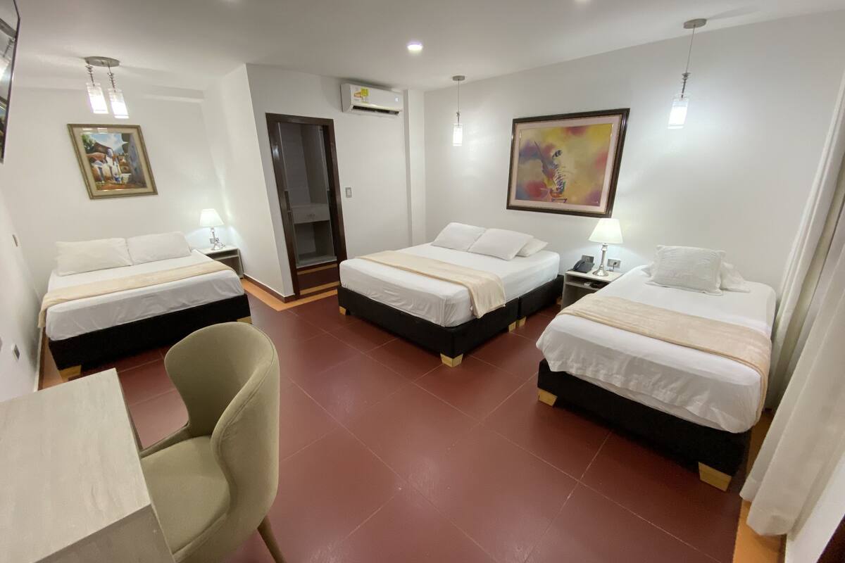 A hotel room with two single beds, a desk, a chair, and a door leading to a closet.