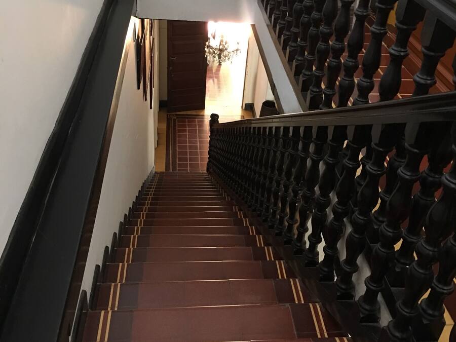 Eine Treppe mit dunkler Geländer und einem weißen Stuhl oben.