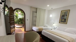 Habitación de hotel con dos camas, una silla, un escritorio, una lámpara y un cuadro en la pared.
