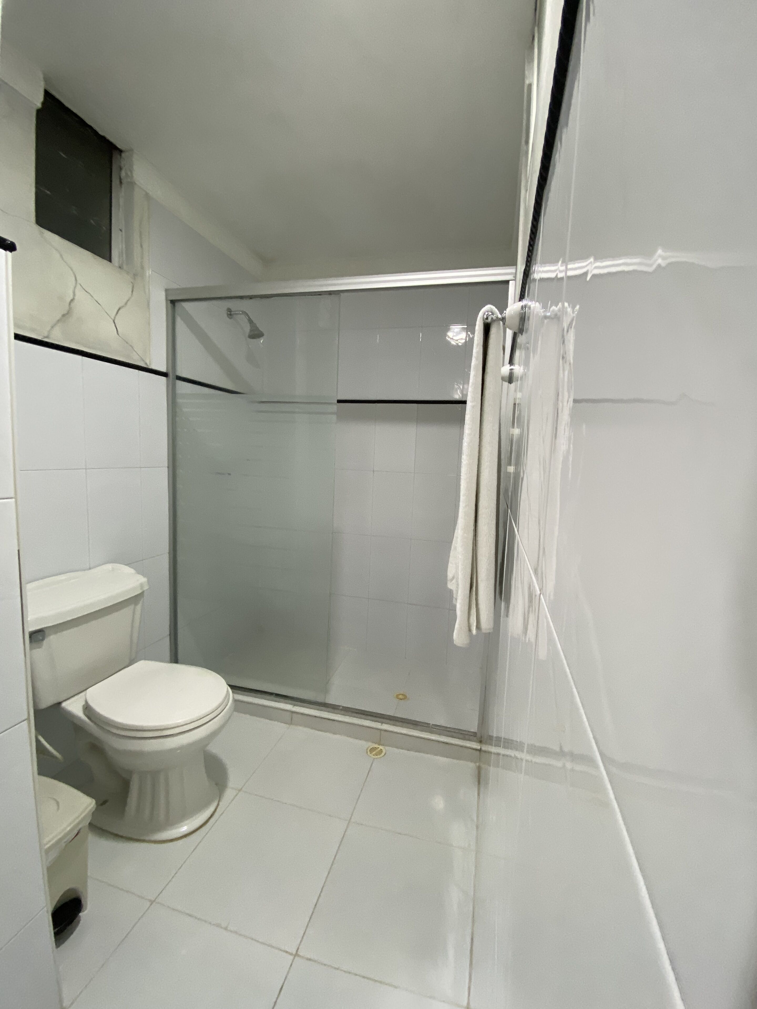Un baño moderno con cabina de ducha de vidrio, inodoro y toallero.