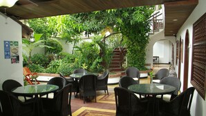Un restaurante con terraza, sillas de mimbre y mesas.