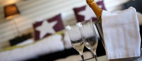 Una mesa de vidrio con dos copas de vino y una botella de champán.
