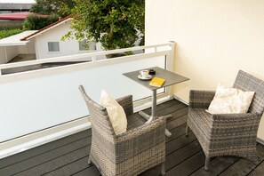 A balcony with wicker chairs, a small table, and a cup of coffee. - Hotel Tiek (Meppen)