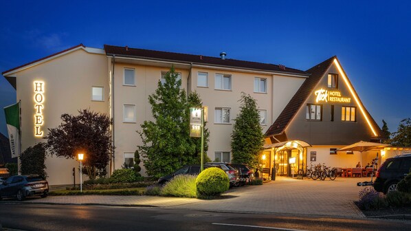 A hotel with a prominent sign, a restaurant, and a well-maintained garden area. - Hotel Tiek (Meppen)
