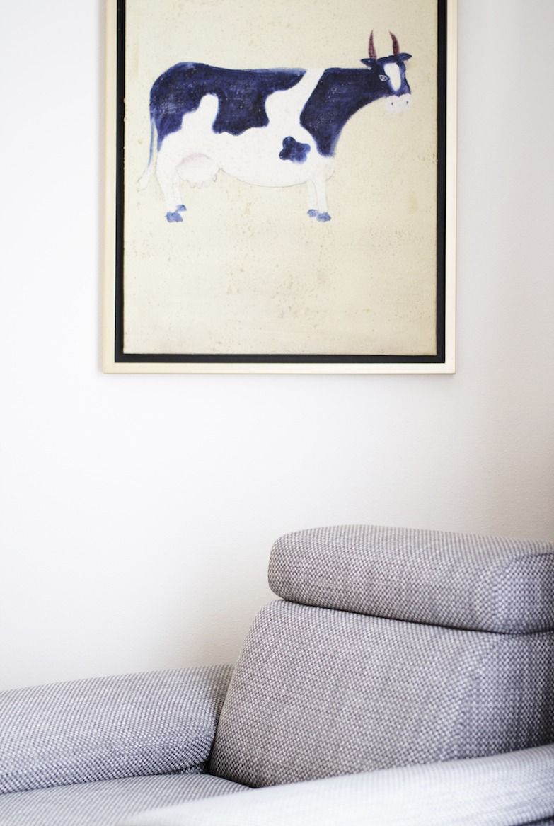 A framed artwork of a cow on a wall.