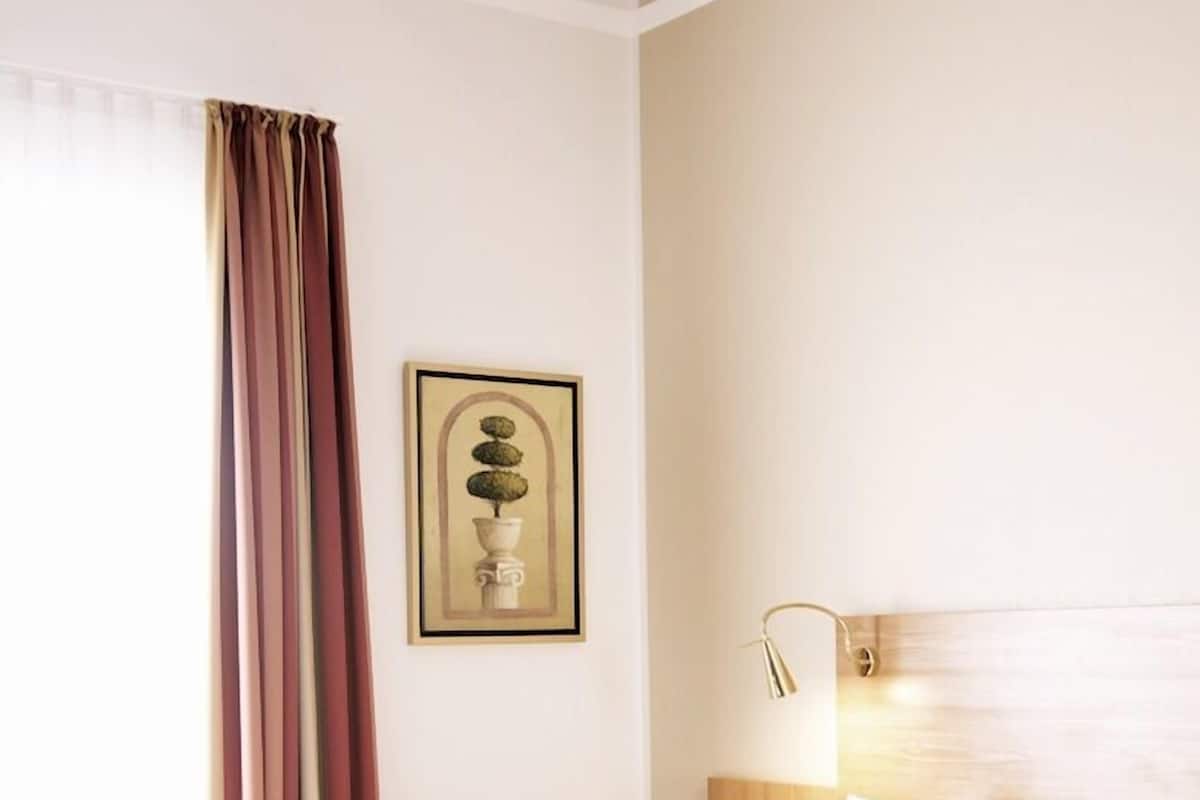 A hotel room with a bed, a nightstand, a lamp, and a framed picture on the wall.