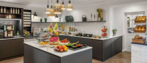 Una cocina moderna con una isla central, electrodomésticos integrados y diversas opciones de comida y bebida.