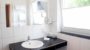 Un baño moderno con encimera negra, lavabo blanco y un espejo grande.