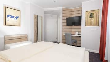 Een hotelkamer met een bed, een bureau, een stoel, een televisie en kunst aan de muren.