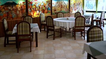 Enjoy dining in a traditional setting with round tables, colorful murals, and comfortable seating.